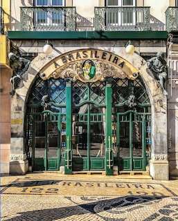 Ornate Art Nouveau entrance of A Brasileira café in Lisbon with decorative arch and green doors