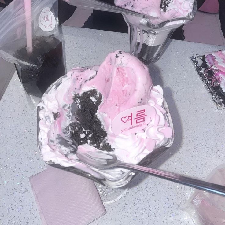 Pink cake with white frosting and black cookie crumbles on white plate