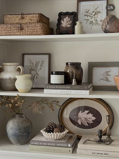 Styled interior shelves with pottery, books, baskets, and framed botanical art in neutral tones