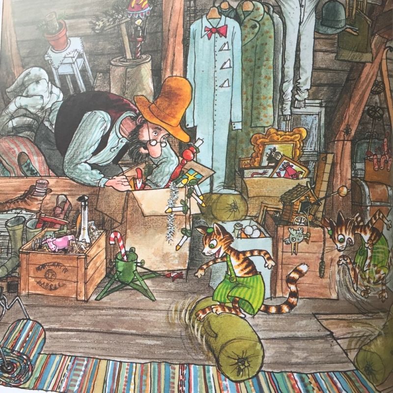 Illustrated attic scene with a man in a large hat, a striped cat, boxes, and old furniture