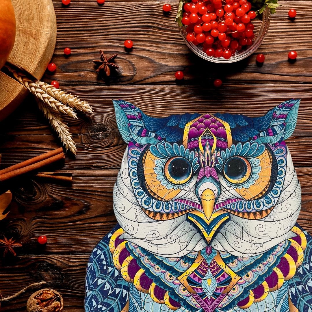 Colorful ornate owl decoration with mandala patterns on wooden table with berries and wheat