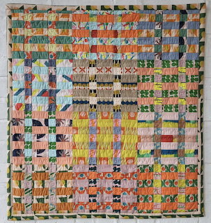 Woven collage artwork made from multicolored paper strips in checkered and striped patterns