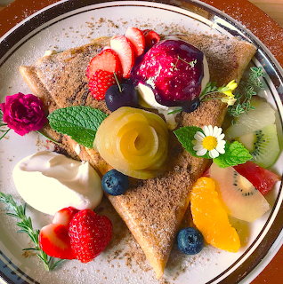Plated dessert with fruit, whipped cream, and ice cream on triangular pastry slices