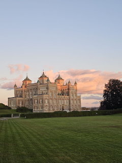 White castle with towers and spires on a green lawn at sunset