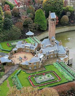 Aerial view of historic estate with tower, formal gardens, and wooded grounds
