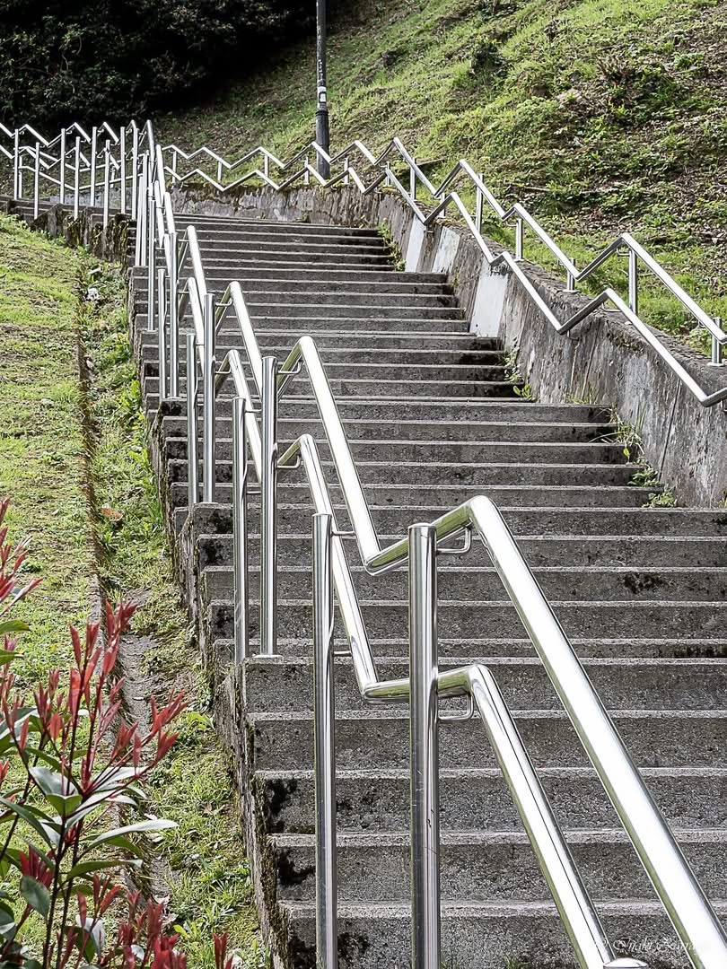 Stone stairway with metal railings climbing up a grassy hillside