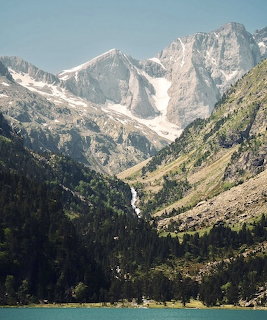 Snow-capped mountain peaks rising above a green valley with an alpine lake