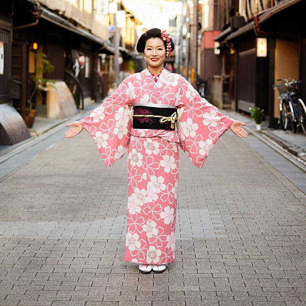 Woman in a pink floral kimono standing on a narrow street