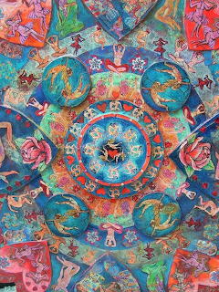 Intricate colorful mandala with circular patterns, flowers, and symmetrical design in turquoise, coral, and pink tones