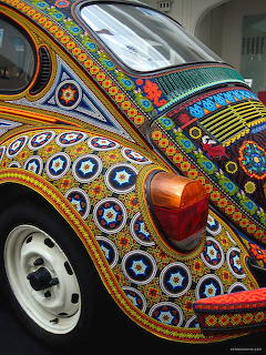 Close-up of a Volkswagen Beetle decorated with colorful hand-painted geometric patterns and circular designs