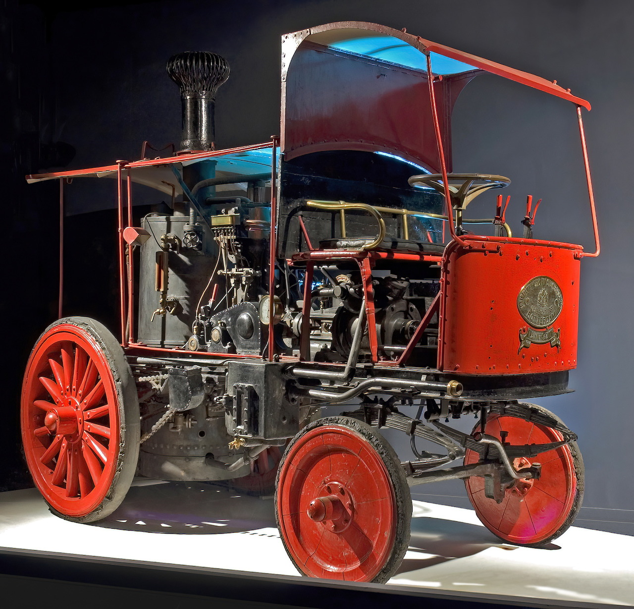 Antique red and black Bikkers steam car displayed in a museum