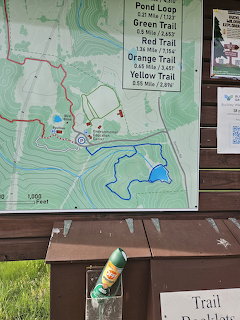 Outdoor trail map sign at Frankfort Park showing colored hiking trails and distances with a water bottle below
