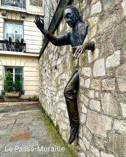 Bronze statue of man walking through stone wall