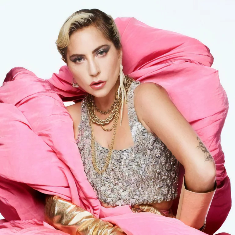 Lady Gaga in silver sequined top with voluminous pink fabric and gold jewelry