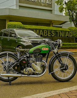 Green vintage BSA motorcycle parked outdoors on pavement