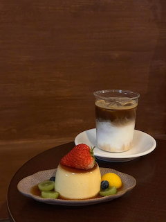 Layered iced coffee drink and flan dessert with strawberry on dark wood surface