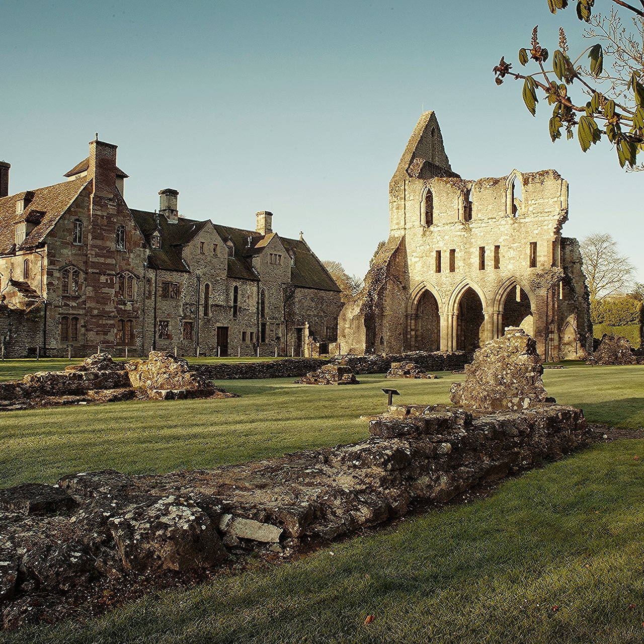 Ancient stone ruins of Wenlock Priory with Gothic arches and green lawns in sunlight