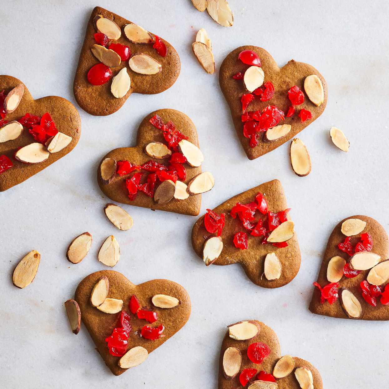 Heart-shaped gingerbread cookies topped with red cherries and almonds