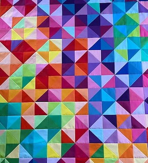 Colorful patchwork quilt with geometric triangle patterns in rainbow colors
