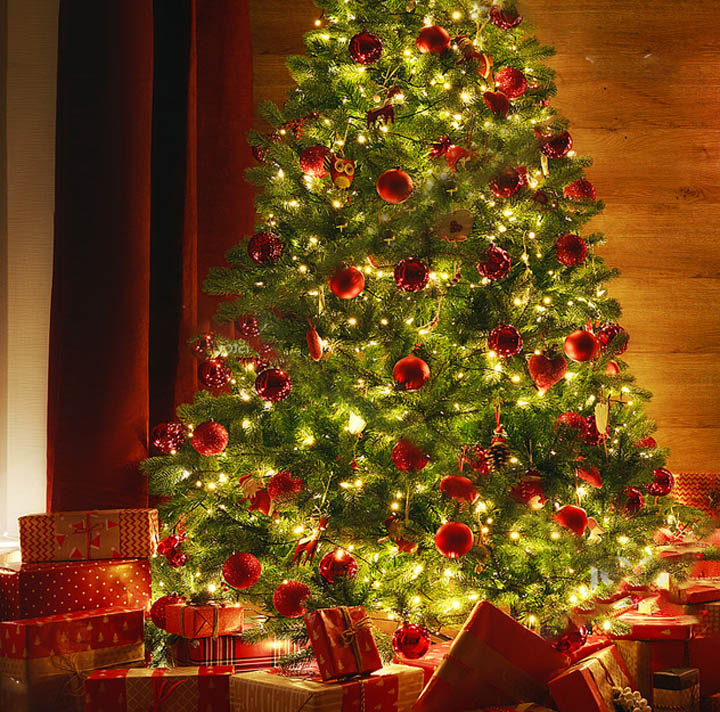 Glowing Christmas tree with red baubles and lights, gifts beneath, warm interior backdrop
