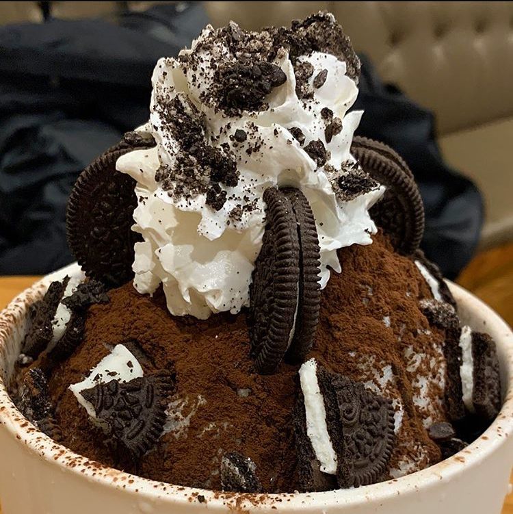 Bowl of chocolate bingsu topped with Oreo cookies and whipped cream