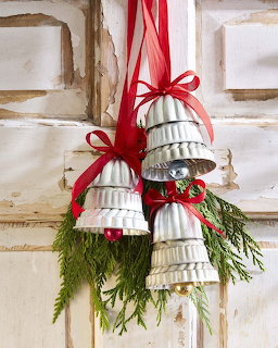 White metal bells with red bows and greenery hanging on a weathered window