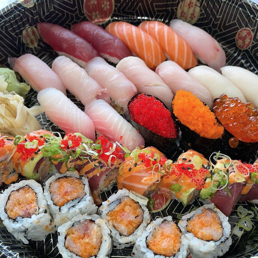Assorted sushi platter with nigiri, sashimi, and decorated maki rolls on a black tray