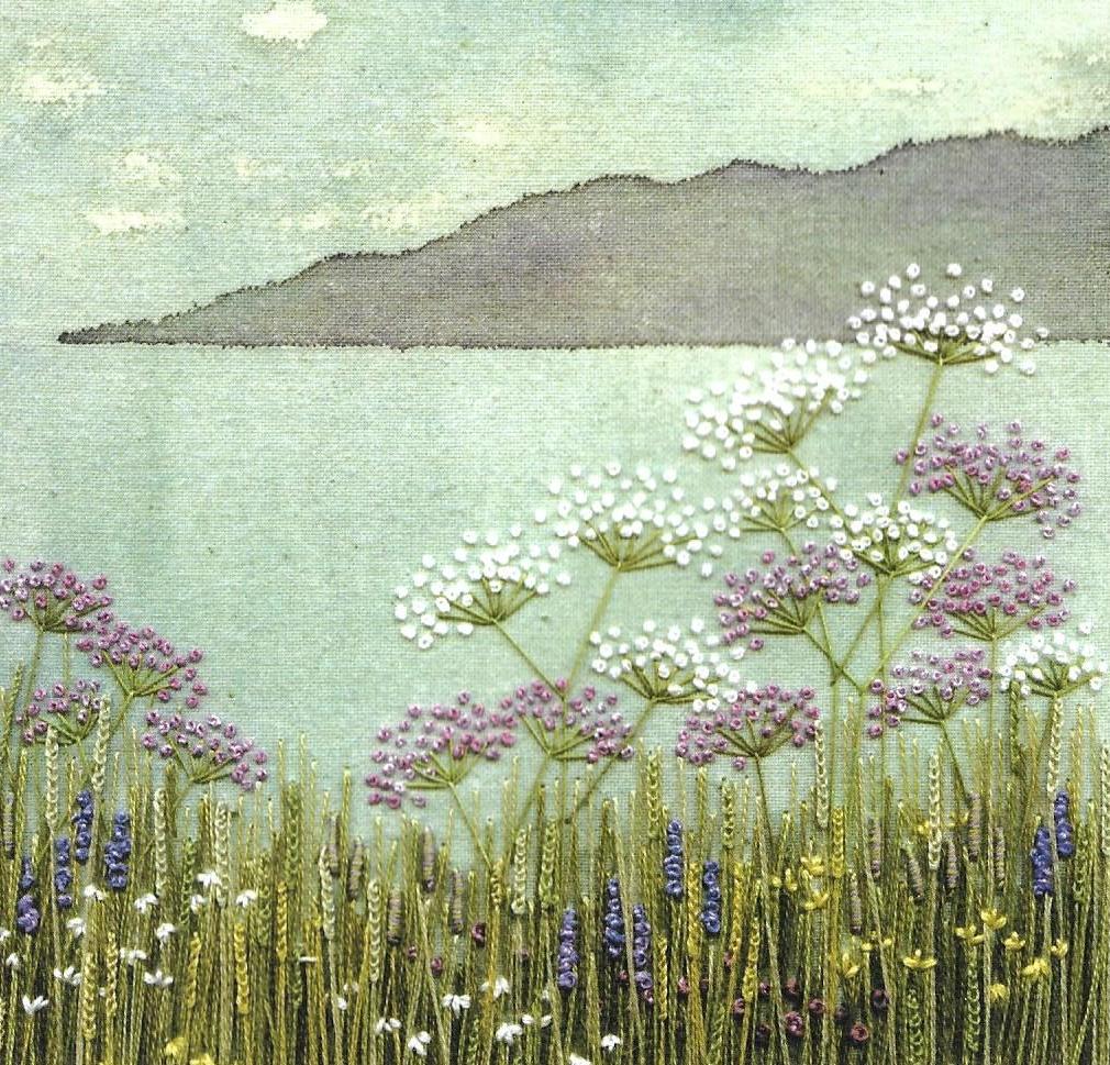 Embroidered scene of wildflowers by a lake with mountain in background