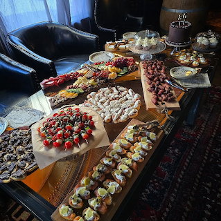 Wooden table covered with assorted desserts, pastries, and chocolate-covered strawberries indoors