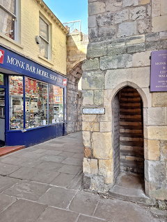 Medieval stone archway with wooden door next to blue-fronted shop on York street