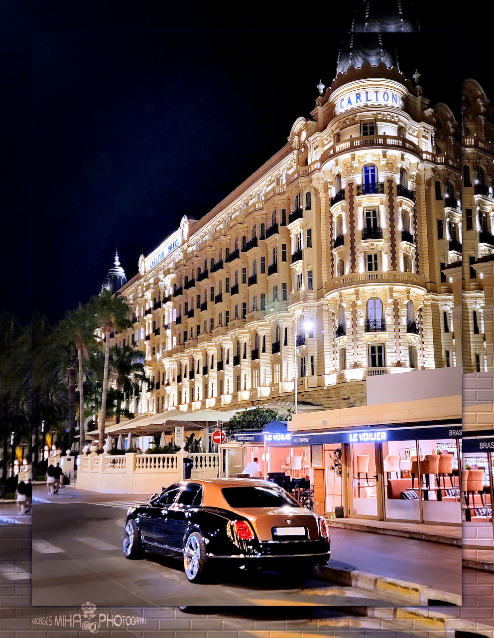 Luxury car parked outside a brightly lit grand hotel facade at night in Cannes