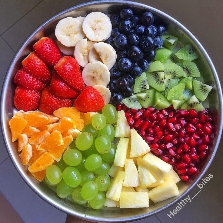 Circular fruit platter with colorful sections of strawberries, bananas, blueberries, kiwi, pomegranate, oranges, grapes, and apples