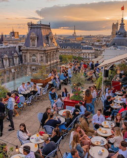 Busy rooftop restaurant terrace in Paris at sunset with Eiffel Tower in the background