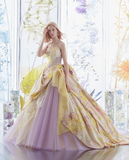 Woman in a strapless pastel floral ball gown with yellow and lavender layers against a floral backdrop