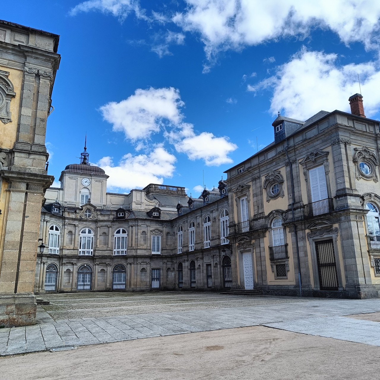 Courtyard of Palacio de La Granja palace in Spain with baroque stone buildings under blue sky