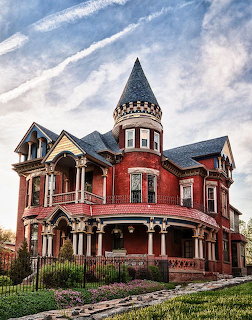 Red brick Victorian house with round turret and porch under cloudy sky
