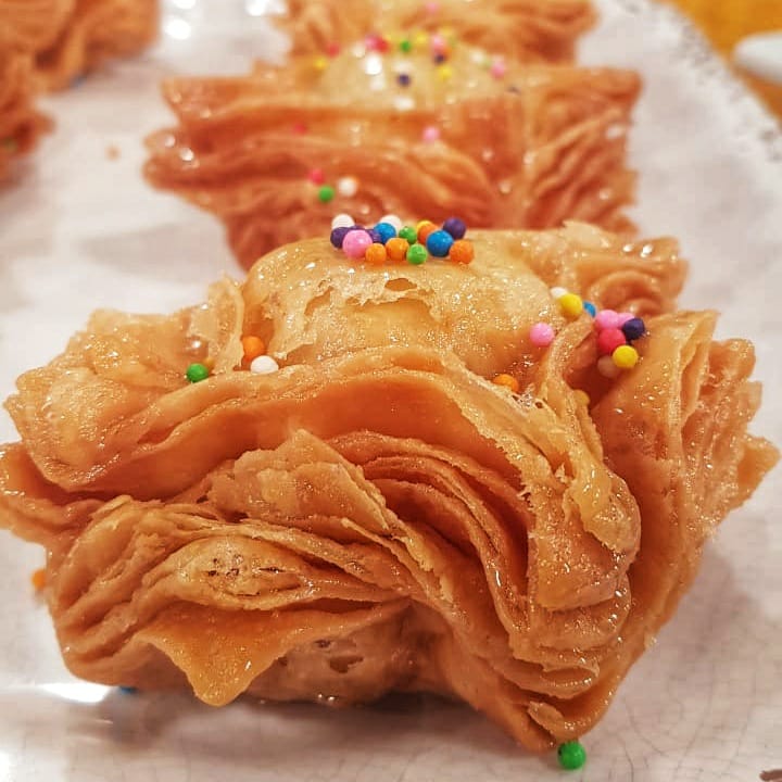 Golden caramel pastries with colorful sprinkles on white parchment paper