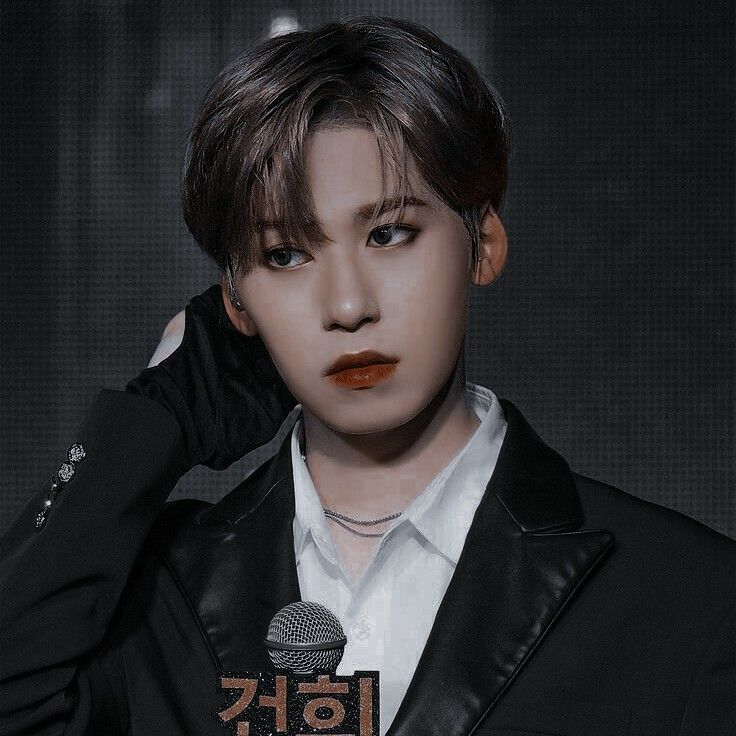 Close-up of Keonhee holding a microphone on stage in a black jacket and white shirt