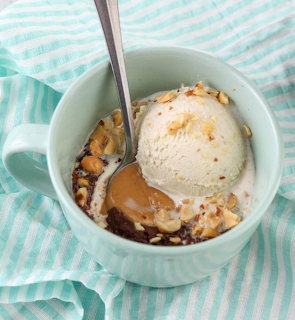 Vanilla ice cream scoop with caramel and nuts in a mint green bowl