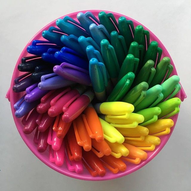 Colorful markers arranged in rainbow spectrum viewed from above in pink cup