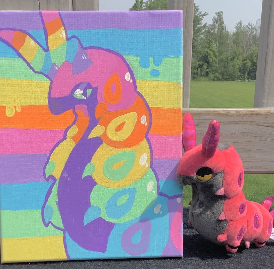 Rainbow alpaca canvas art next to a pink alpaca plush toy