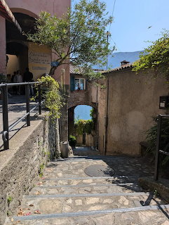 Stone stairway in Gandria village with an archway and a view of the blue lake beyond