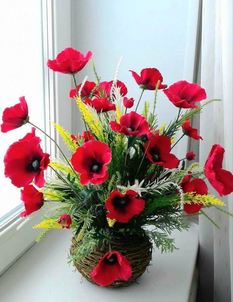 Red poppy bouquet in a basket vase on a white windowsill