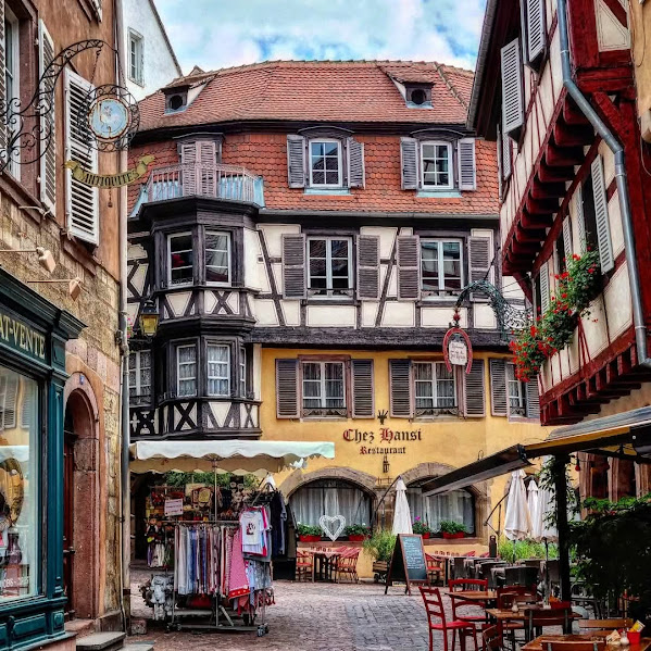 Half-timbered buildings with outdoor café tables in a cobblestone European courtyard