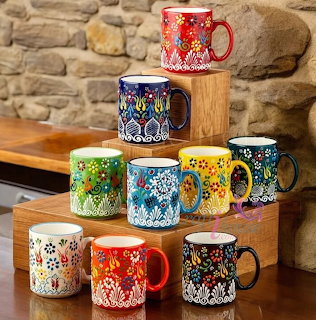 Stack of colorful patterned ceramic coffee mugs arranged on wooden blocks
