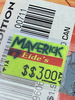 Close-up of a neon yellow Maverick price sticker with barcode and handwritten text