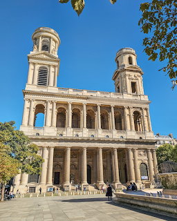 Neoclassical facade of Saint-Sulpice Church in Paris with two bell towers and colonnades under a blue sky