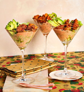 Three martini glasses with layered savory appetizers on a festive table setting