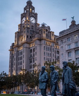 Royal Liver Building clock tower at dusk with Beatles statues in foreground