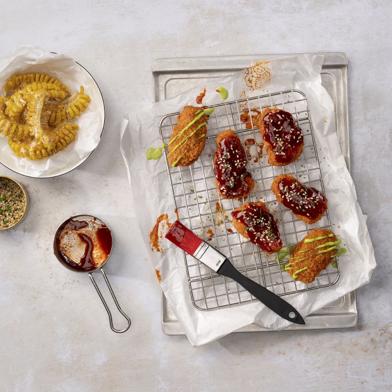 Glazed vegan wings on cooling rack with corn and sauce